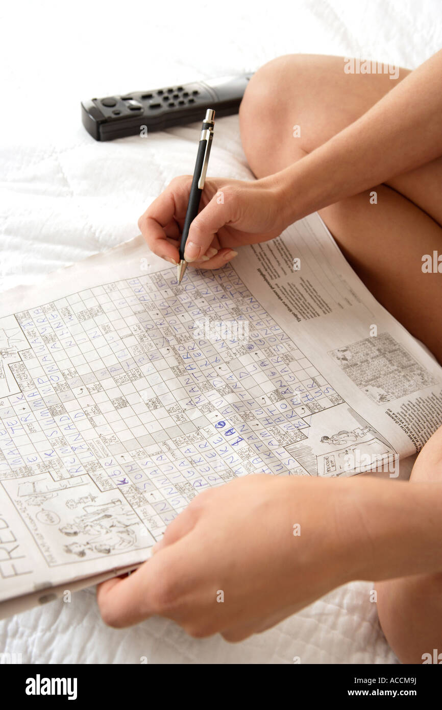 person solving crossword puzzle with pencil